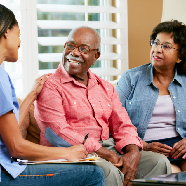 Nurse Making Notes During Home Visit With Senior Couple